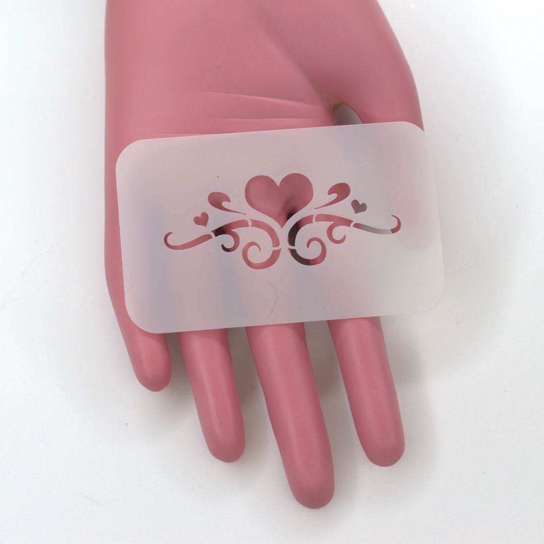 Little Heart with swirls cut into PET as a stencil sitting on fake pink hand