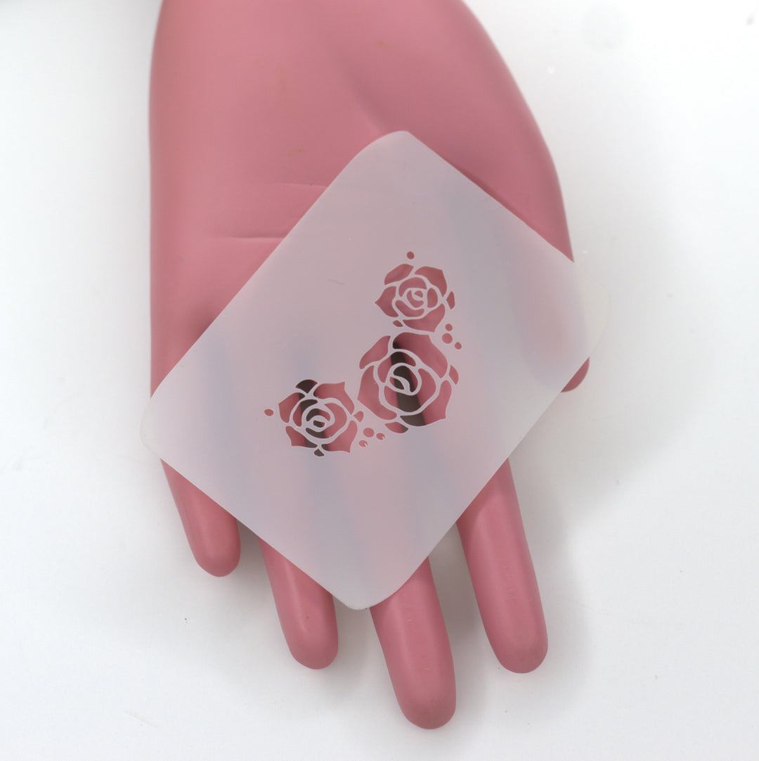 PET stencil of three roses on pink hand