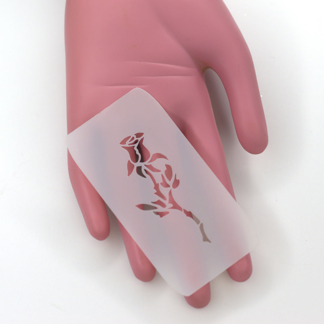 white PET stencil of small rose bud held by pink hand