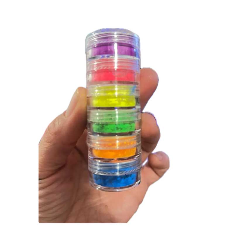 human hand holding stack of six clear jars filled with neon pigments